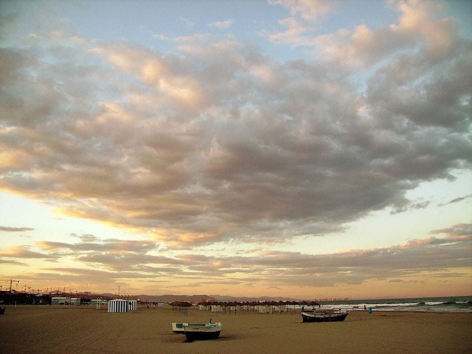 Cielo con nubes anaranjadas sobre el horizonte, visto desde la playa de la Malvarrosa