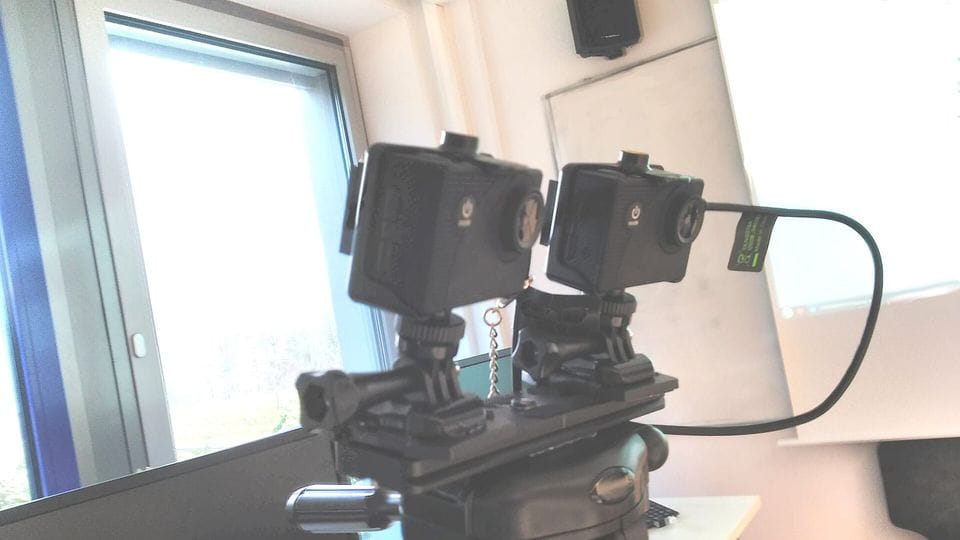 Dos cámaras pequeñas montadas en un trípode junto a una ventana