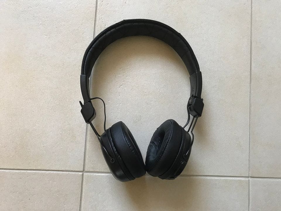 Auriculares negros de diadema sobre un suelo de baldosas claras