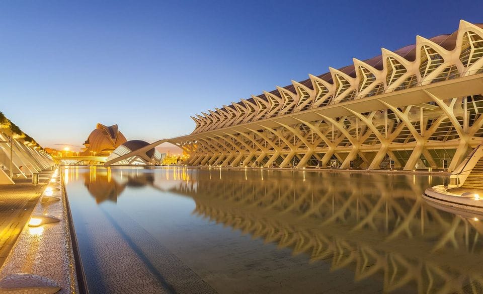 Edificio de arcos blancos junto a un estanque al atardecer, en la Ciudad de las Artes y las Ciencias de Valencia